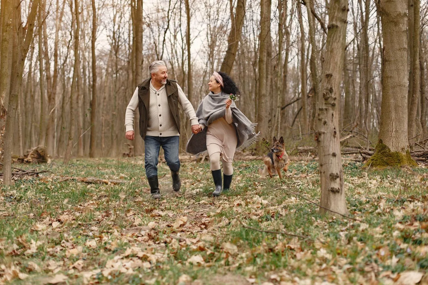 An older adult walking her dog with support nearby.